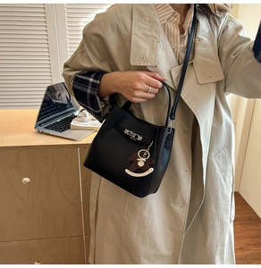 Detail of black lychee grain leather bucket bag with silver lock and horse pendant