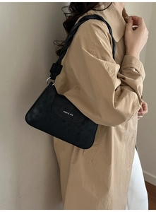 Close-up of black retro leather shoulder bag with silver hardware on khaki coat