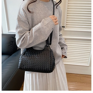 Detailed view of black woven leather texture and Intrecciato craftsmanship on the handbag