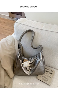 Detailed view of bronze hobo bag with vintage leather texture and plush charm on white sofa