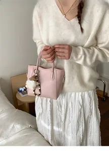 Détail du sac seau en cuir rose pâle avec breloque et poignée en perles de bois