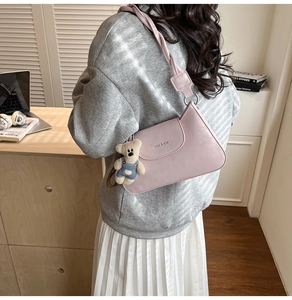 Pink PU leather baguette bag with branding detail and cute plush bear charm accessory