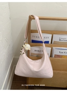 Detail of pink glossy tote bag with decorative pearl charm and crinkled texture finish