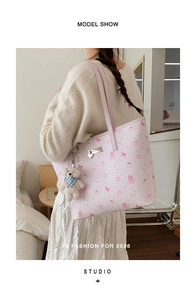 Fashionable pink tote bag with cute cartoon prints and plush bear charm shown on model