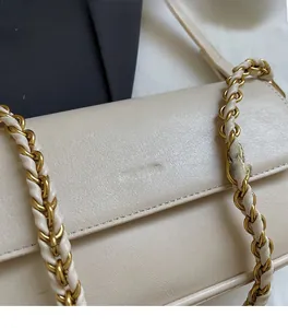 Detail of the cream baguette bag with NO FILTER gold embossing and a chain strap