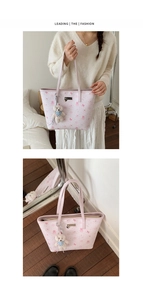 Detail of pink PU tote bag featuring embossed texture and a white plush bear charm