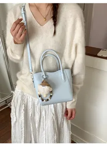 Détail du sac seau bleu clair avec breloque Père Noël et lanière perlée sur un mannequin