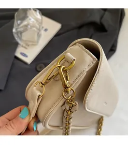 Close-up of durable gold-tone metal hardware and leather strap on a cream baguette bag