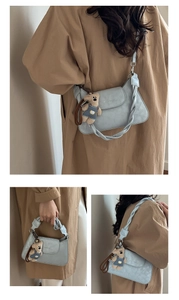 Detail of grey-blue shoulder bag with woven handle and cute bear charm accent