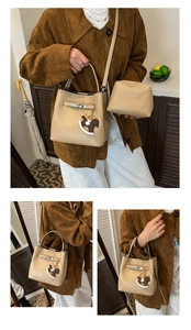 Detail of beige lychee grain leather bucket bag with horse charm and silver lock