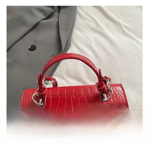 Close-up of red crocodile embossed handbag with silver metal lock and curved handle