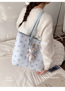 Close-up of light blue printed tote bag with plush puppy pendant and cute heart patterns