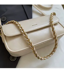 Detail of beige faux leather baguette bag with gold chain strap on grey blazer