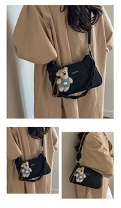 Detail of black square shoulder bag with brand logo and cute plush bear accessory