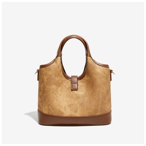 Close-up of vintage brown canvas bucket bag showing faux leather trim and metal hardware