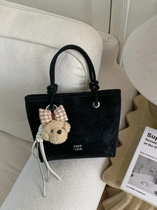 Minimalist black suede tote bag with rope handle and cute puppy pendant on sofa