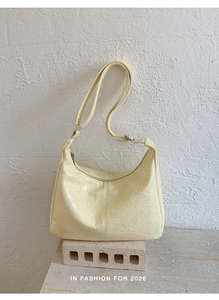 Detail of pale yellow tote bag with pleated shiny texture on industrial brick background
