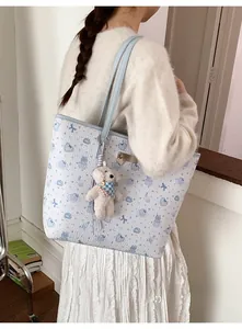 Detail of light blue tote bag with cute cartoon rabbit prints and a plush puppy charm