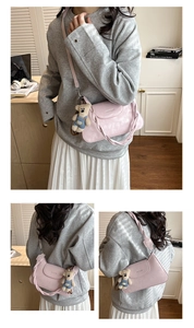 Detail of pink shoulder bag featuring braided strap and cute teddy bear charm
