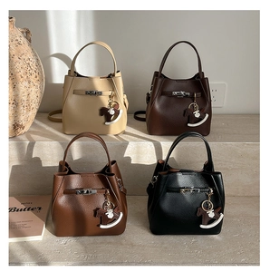Detail view of four textured leather bucket bags with charms on stone steps