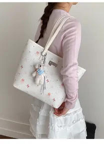 Detailed view of white embossed tote bag featuring cute pink cat and cake illustrations