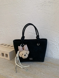 Minimalist black matte tote bag with rope handles and plush poodle tassel charm