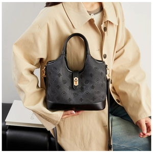 Detail of vintage black tote bag with floral embossing and gold metal twist lock