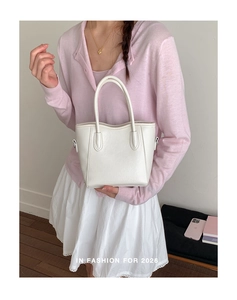 Détail du sac seau en cuir blanc avec poignée fixe porté par un mannequin en douceur