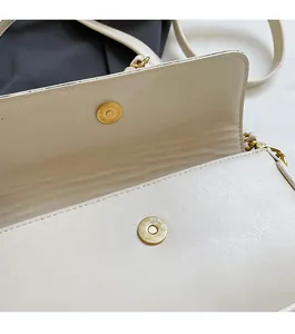 Close-up of cream leather baguette bag showing champagne gold magnetic buckle detail