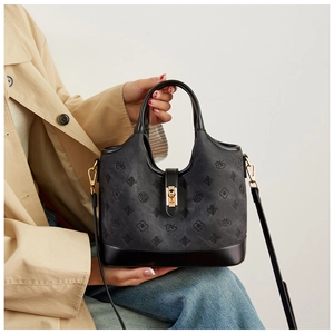 Detail of black leather handbag with embossed floral patterns and metal twist lock closure