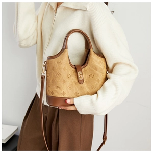 Close-up of retro bucket bag with embossed monogram patterns and metal twist lock