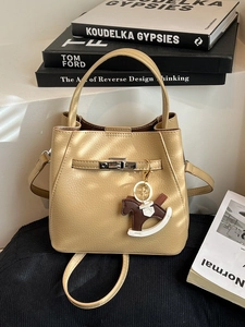 Champagne gold lychee leather bucket bag with silver lock and horse charm on books