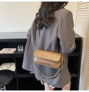 Detail of vintage brown baguette bag with golden chain strap on gray blazer