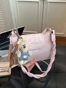 Pink PU leather crossbody bag with woven strap and a cute blue teddy bear pendant