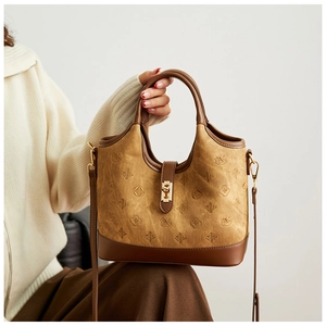 Detailed view of camel faux suede bucket bag with gold swan lock and embossed patterns