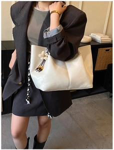 Détail du sac fourre-tout blanc crème avec breloque fleurie sur un mannequin femme