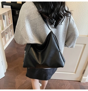 Detail of matte black leather Hobo bag with fashion brand tag on shoulder strap