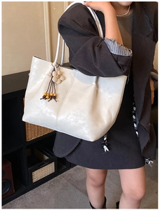 Détail d'un sac cabas en cuir blanc avec pendentif floral et gland en perles de bois