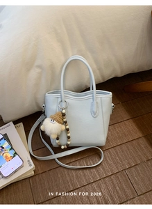 Détail du sac à main bleu clair en cuir avec bord ondulé et accessoire en peluche doux