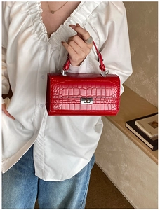 Macro detail of red crocodile embossed leather handbag with silver metallic turn-lock