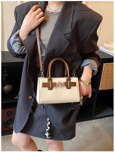 Close-up of cream and brown square handbag with metal buckle detail and top handle