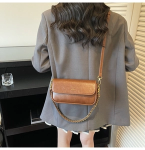 Brown faux leather baguette bag featuring a gold chain strap and vintage flap design