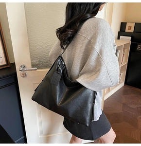 Detailed view of a black oversized PU leather tote bag worn as a shoulder bag