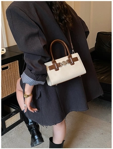 Detailed side view of off-white retro square bag with contrast brown trim and metal chain