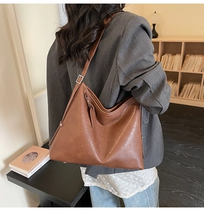 Brown leather tote bag worn by a model showcasing its large capacity and soft matte texture