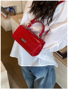 Detail of red crocodile texture handbag with silver metal twist lock and shoulder strap