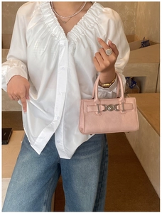 Detail of light pink Boston handbag featuring a heart-shaped lock buckle and handle