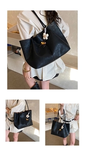 Détail d'un grand sac fourre-tout noir avec pendentif floral porté sur une robe chemise