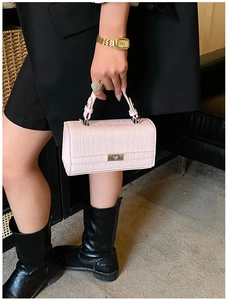 Close-up of pink crocodile pattern texture and silver metallic twist lock on handbag