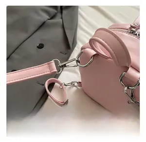Macro detail showing high-quality silver metal hooks and pink leather strap on handbag
